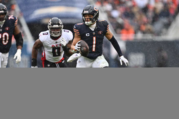 Dec 31, 2023; Chicago, Illinois, USA; Chicago Bears quarterback Justin Fields (1) scrambles away from outside linebacker Lorenzo Carter (0) for yards in the first half against the Atlanta Falcons at Soldier Field.